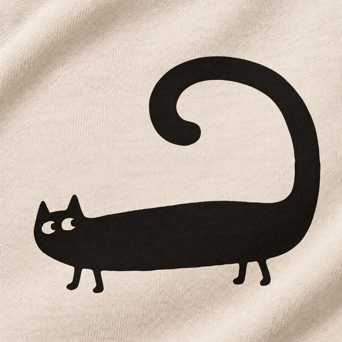 Close-up of the black cat and curled tail printed on cream sweatshirt fabric.