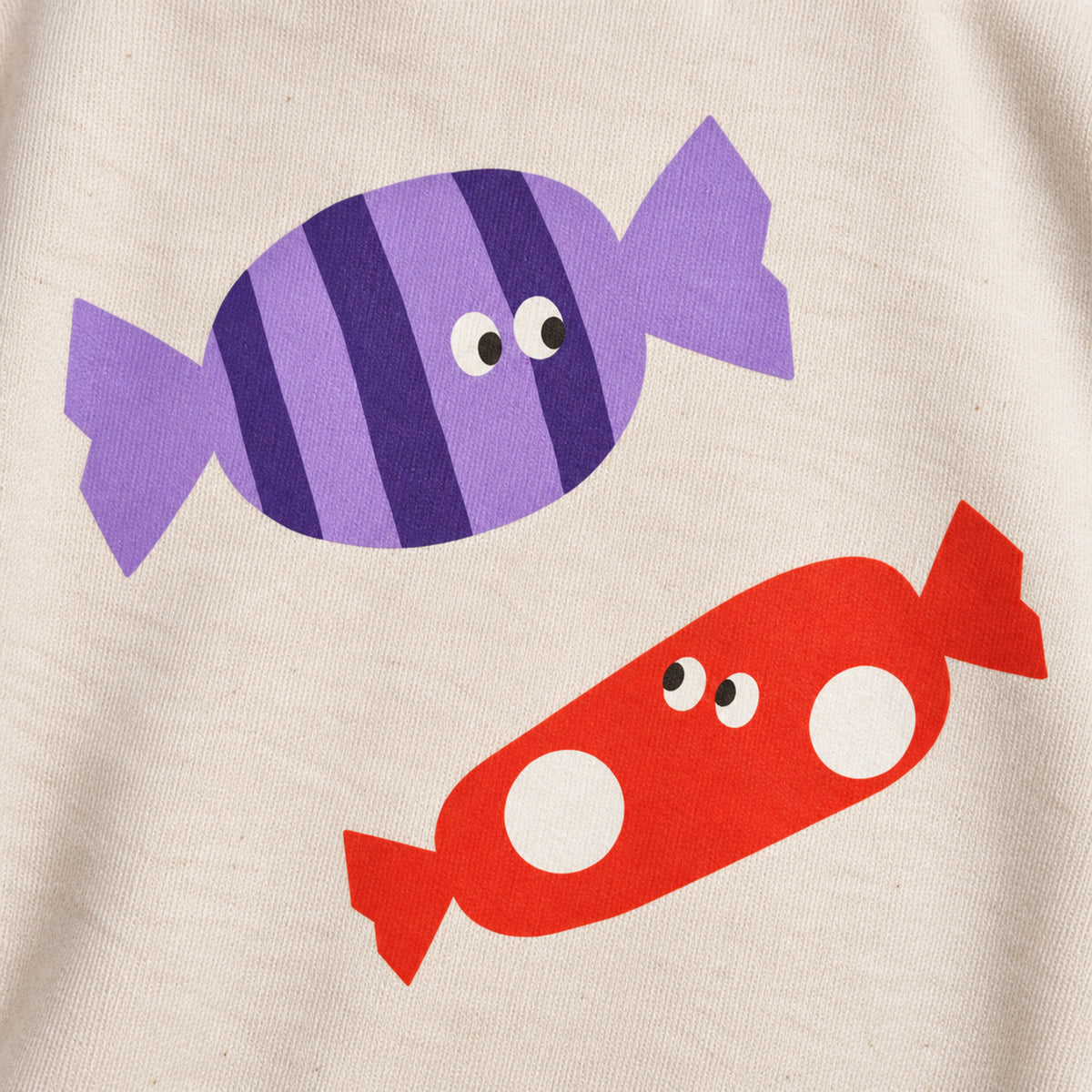 Close-up of purple striped and red-orange spotted sweet illustrations printed on cream sweatshirt fabric.