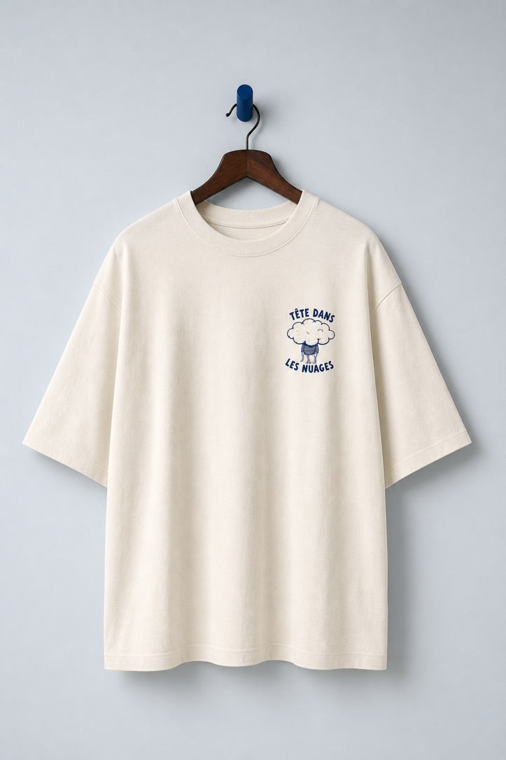 Tête dans les Nuages Natural Raw organic cotton T-shirt on a hanger, showing the small navy cloud chest print.